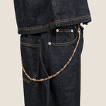 ICED London dark denim jeans with a rose-gold chain draped from a belt loop to the front pocket, close-up side view.