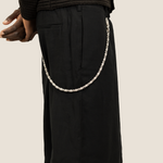 ICED London: close-up of black shorts with a silver chain attached to the belt loop, side view.